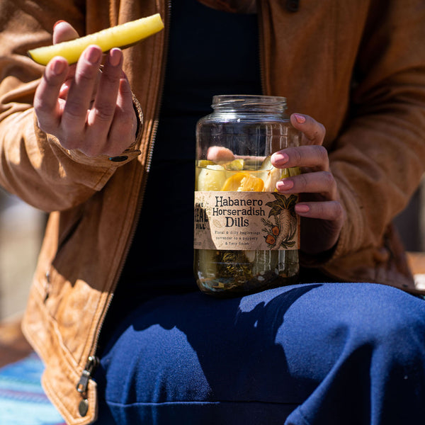 Person eating from a jar of Habanero Horseradish Dills